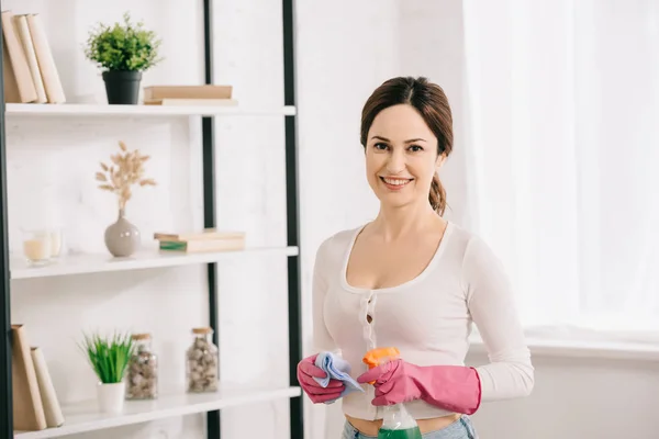 Attraktive Hausfrau Lächelt Die Kamera Während Sie Lappen Und Sprühflasche — Stockfoto