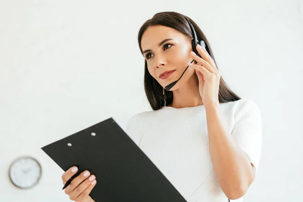 Attractive Broker Touching Headset While Holding Clipboard Office — Stock Photo, Image