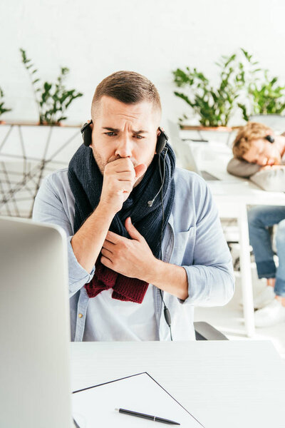 селективное внимание брокера в шарфе кашляет рядом с коллегой в офисе
 