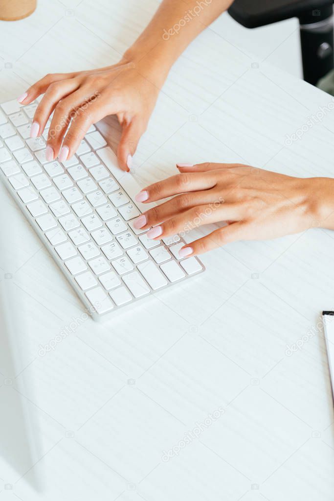 cropped view of woman typing on computer keyboard in office 