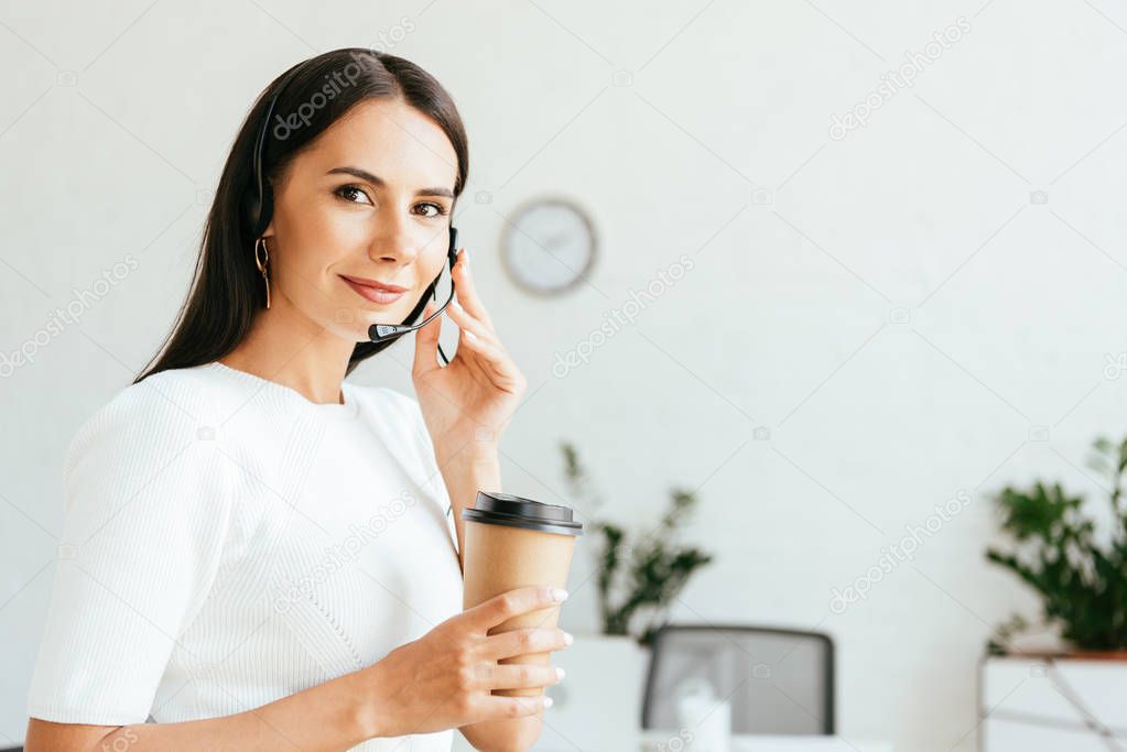 happy broker touching headset and holding paper cup 