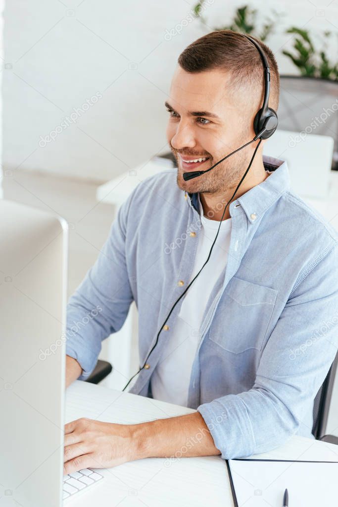 happy operator in brokers agency typing on computer keyboard while looking at computer monitor 