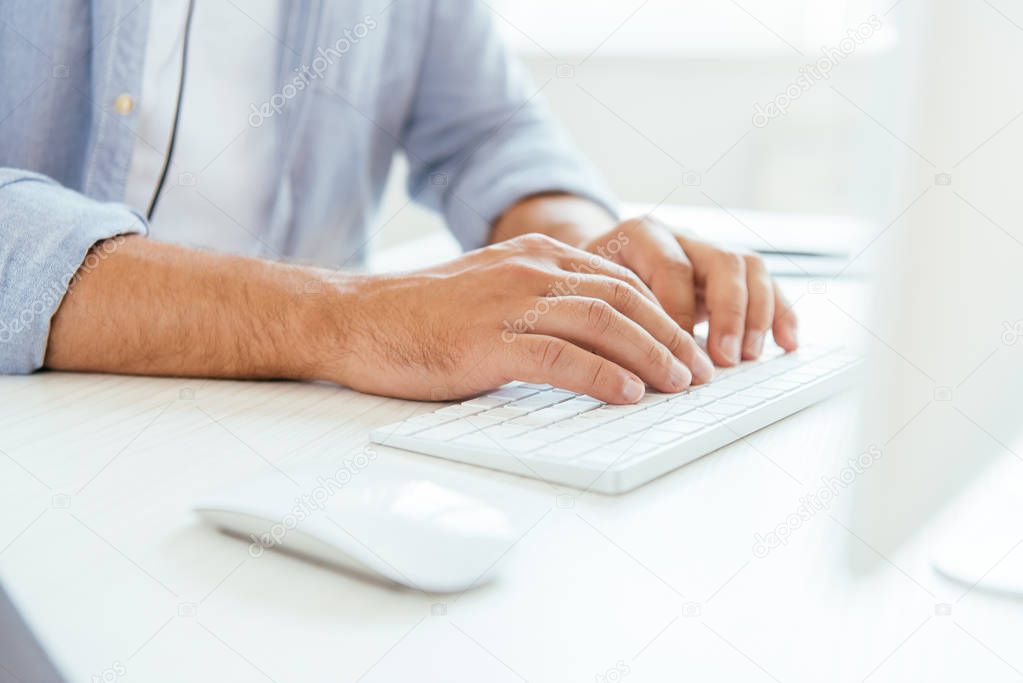 cropped view of broker typing on computer keyboard near computer mouse 