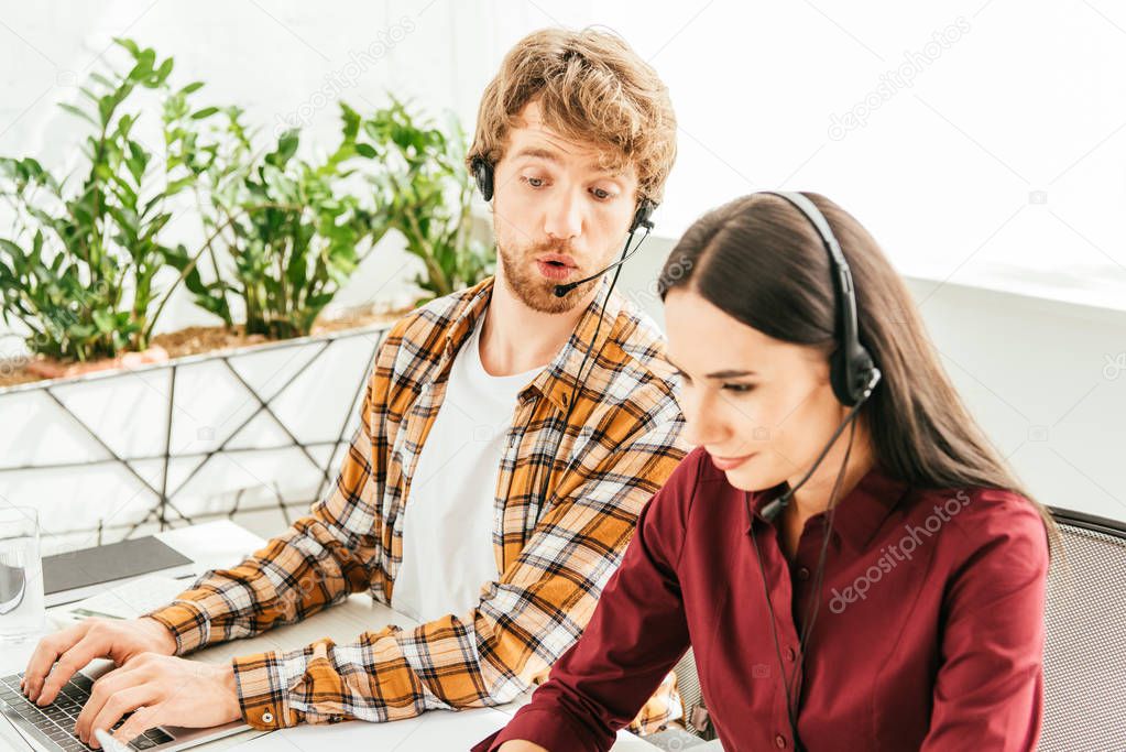 Selective focus of surprised breaded broker near attractive coworker in office