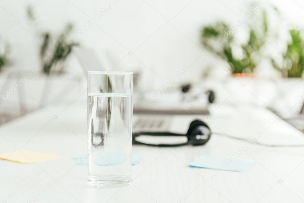 selective focus of glass with water near headsets in office 