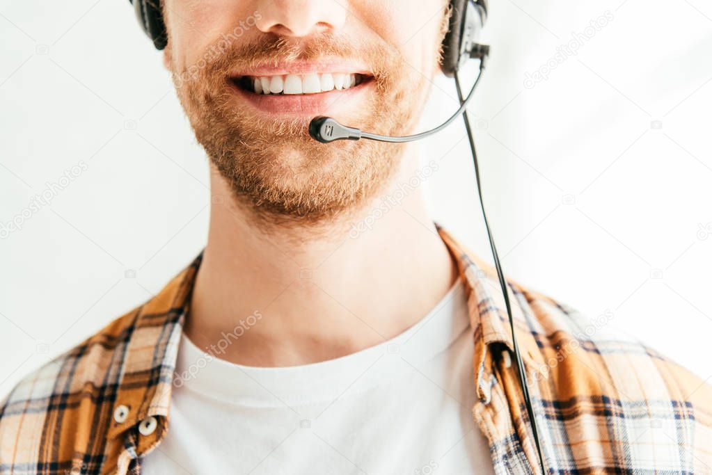 cropped view of bearded broker in headset smiling in office 