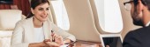 Panoramaaufnahme von Geschäftsmann mit digitalem Tablet und Geschäftsfrau im Privatflugzeug 