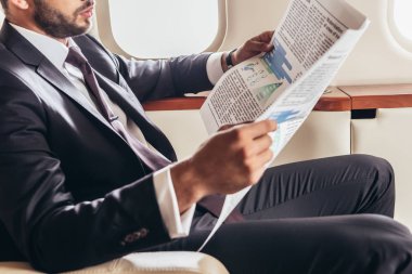 Takım elbiseli işadamının özel uçakta gazete okuması. 