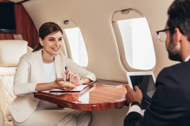 İşadamlarının seçici odak noktası dijital tablet ve iş kadınlarının özel uçakla konuşmaları. 