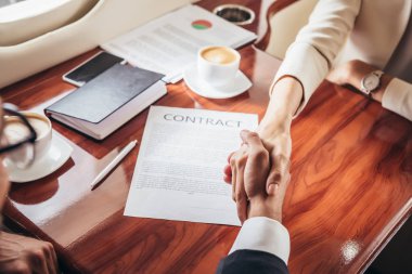 cropped view of businessman and businesswoman shaking hands in private plane  clipart