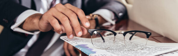 panoramic shot of businessman in suit taking glasses in private plane 