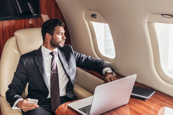 Hombre Negocios Guapo Traje Mirando Través Ventana Sosteniendo Teléfono Inteligente —  Fotos de Stock