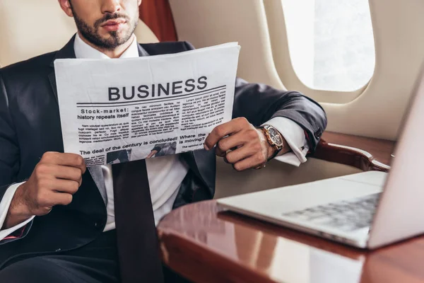 スーツ姿のビジネスマンが民間航空機でビジネス新聞を読む姿を切り取り — ストック写真