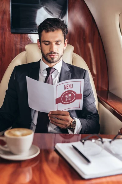 自家用機内のメニューを見るスーツ姿のハンサムなビジネスマン — ストック写真