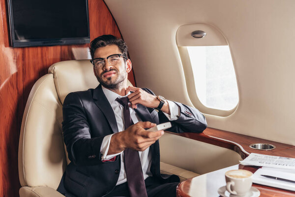 handsome businessman in suit holding remote controller in private plane 