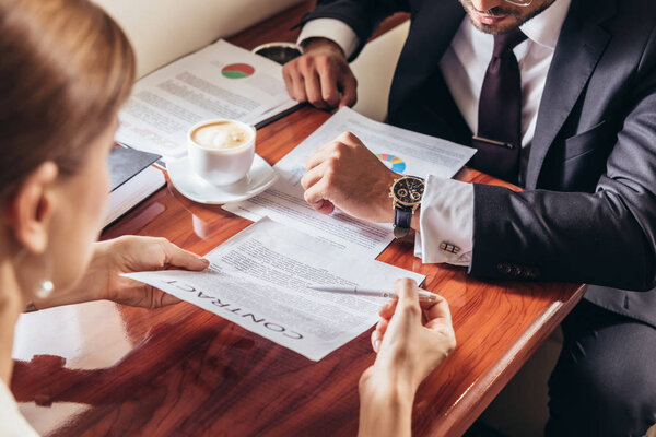 cropped view of businesswoman showing contract to businessman in private plane 
