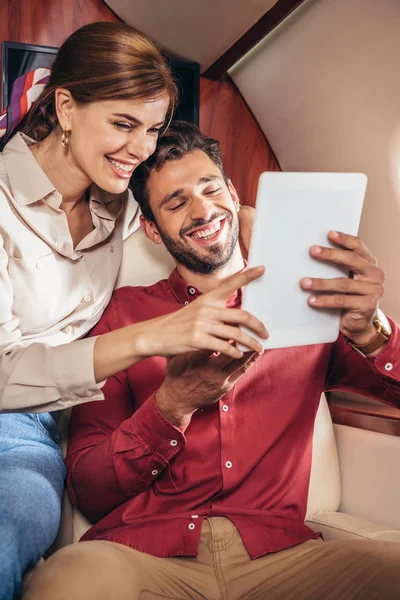 笑着在私人飞机上拿着数码平板电脑的男女朋友 — 图库照片