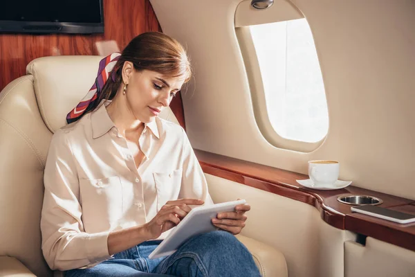 私人飞机上使用数码平板电脑的T恤美女 — 图库照片