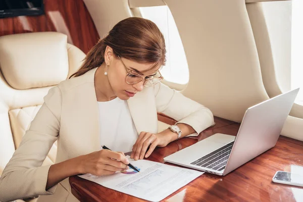 民間航空機で書類作成をするスーツ姿の魅力的なビジネスウーマン — ストック写真
