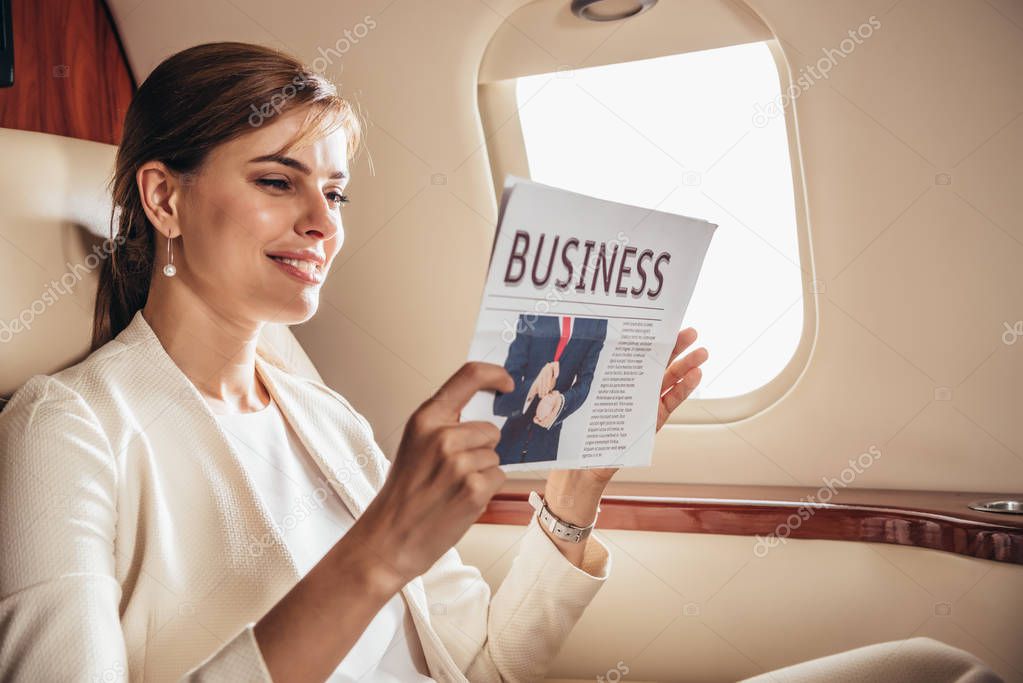 attractive businesswoman in suit writing reading newspaper business in private plane 