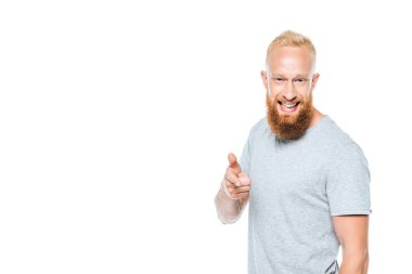cheerful bearded man in grey t-shirt pointing at you isolated on white