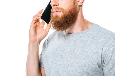 Akıllı telefondan konuşan sakallı, beyaz tenli ciddi bir adamın görüntüsü.