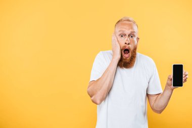 Akıllı telefonu boş ekranla gösteren şok adam, sarı ekranda izole edilmiş.