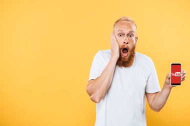 Kyiv, Ukrayna - 27 Ağustos 2019: şok olmuş bir adam Youtube uygulamalı akıllı telefon gösteriyor, sarıda izole edilmiş.