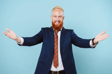 Takım elbiseli neşeli sakallı iş adamı, kolları açık, mavi üzerinde soyutlanmış.
