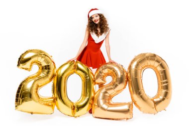 Noel Baba kostümlü çekici kız 2020 'de altın balonlarla poz veriyor, beyaz tenli.