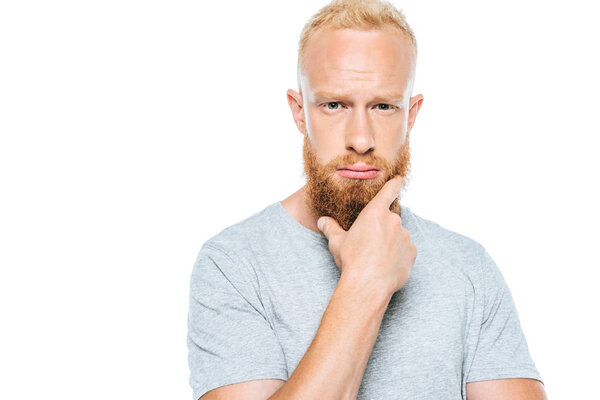 задумчивый бородатый мужчина в серой футболке, изолированный на белом
