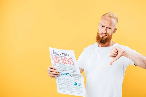 留着胡子的男人拿着假新闻的报纸 用大拇指朝下看 用黄色隔开 — 图库照片