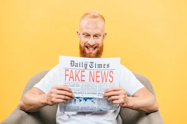 Sorridente Homem Lendo Jornal Com Notícias Falsas Enquanto Sentado Poltrona — Fotografia de Stock