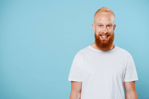 portrait of handsome smiling bearded man in white t-shirt, isolated on blue 