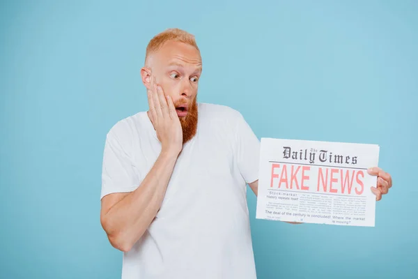 Geschockter Mann Sieht Zeitung Mit Fake News Isoliert Auf Blauem — Stockfoto