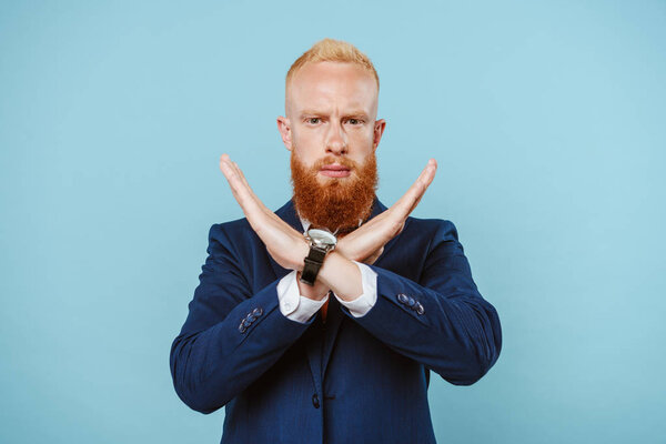 serious bearded businessman in suit showing no sign, isolated on blue