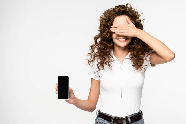 Smiling Curly Girl Closing Eyes Showing Smartphone Blank Screen Isolated — Stock Photo, Image