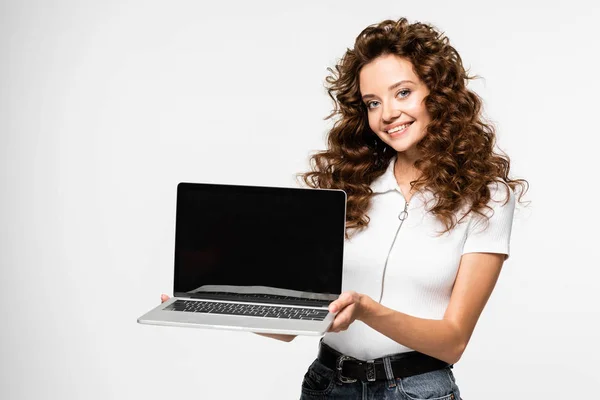 Gelukkig Krullende Vrouw Presenteren Laptop Met Blanco Scherm Geïsoleerd Wit — Stockfoto