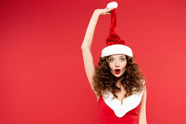 Attraktiv Förvånad Flicka Poserar Santa Kostym Och Hatt Isolerad Rött — Stockfoto