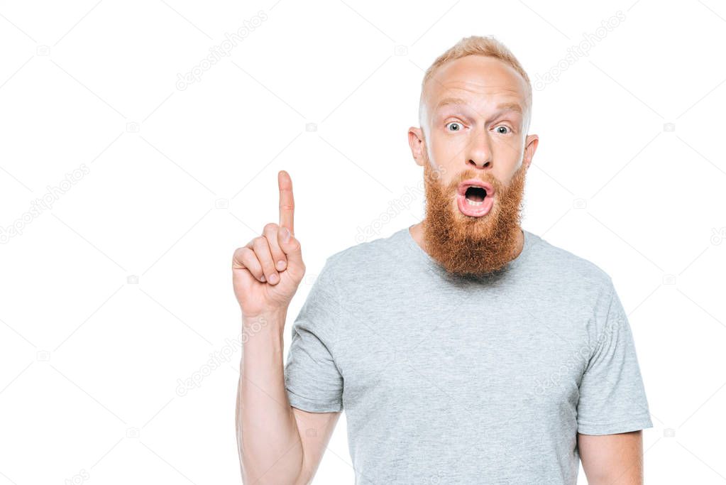 shocked bearded man in grey t-shirt pointing up, isolated on white