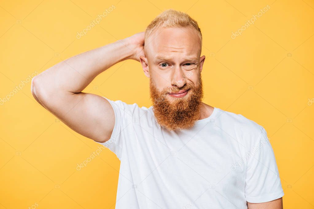 portrait of handsome confused bearded man, isolated on yellow