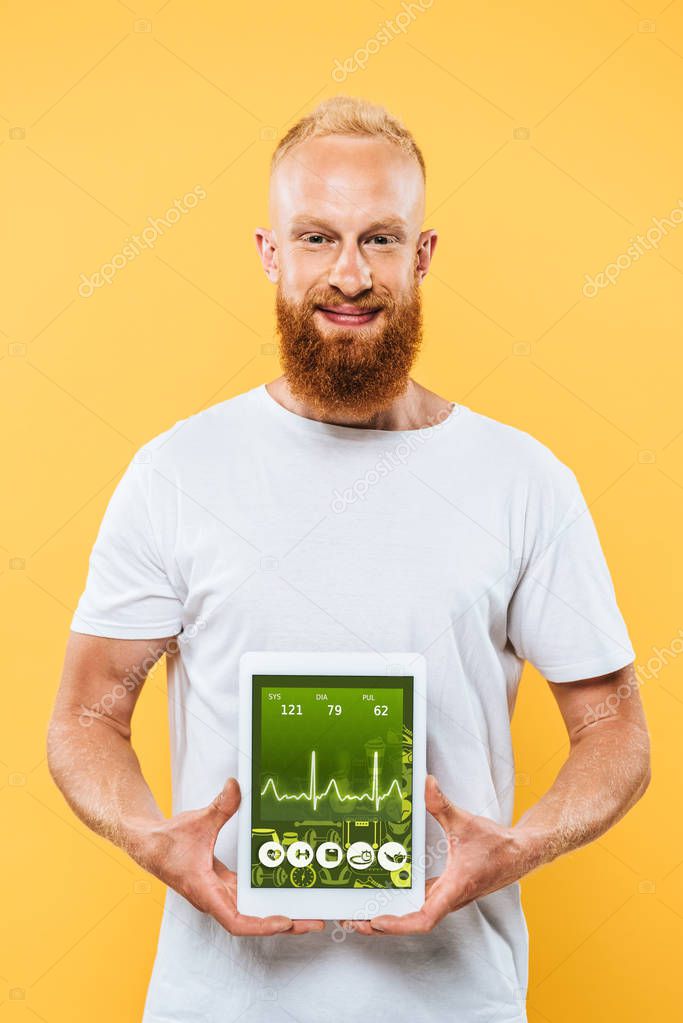 Bearded man showing digital tablet with on health app screen, isolated on yellow
