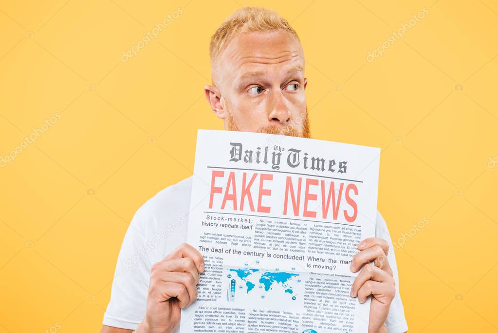 worried man holding newspaper with fake news, isolated on yellow