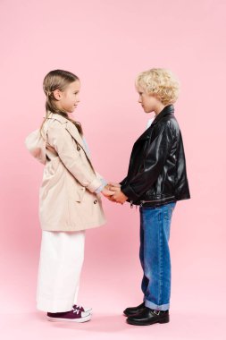 Pembe arka planda el ele tutuşan çocukların yan görüntüsü 