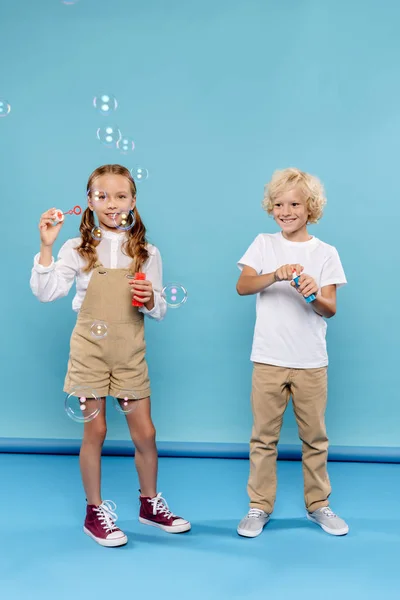 Glimlachen Leuke Kinderen Blazen Zeepbellen Blauwe Achtergrond — Stockfoto