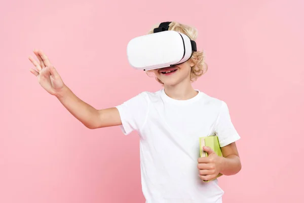 Niño Sonriente Con Auriculares Realidad Virtual Ondeando Sosteniendo Libro Aislado — Foto de Stock