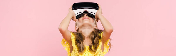 panoramic shot of kid with virtual reality headset looking up isolated on pink