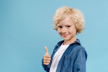 Gülümseyen ve tatlı bir çocuk kameraya bakıyor ve mavi üzerinde izole edilmiş gibi görünüyor. 