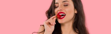 Kırmızı dudaklı, pembe izole edilmiş çilek yiyen mutlu bir kadının panoramik görüntüsü. 