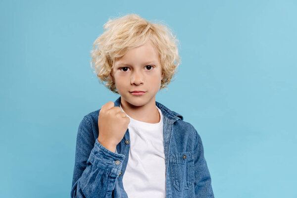 симпатичный малыш, смотрящий на камеру и показывающий фист на голубом фоне
 